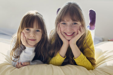 Portrait of happy siblings relaxing on bed at home - CAVF43960