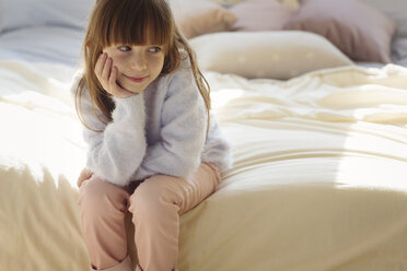 Nachdenkliches Mädchen auf dem Bett sitzend - CAVF43963