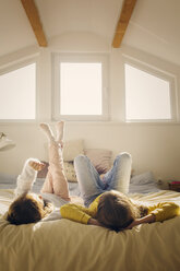 Sisters resting while lying on bed at home - CAVF43965