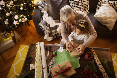 Overhead-Ansicht von Mädchen und Großmutter Verpackung Geschenk am Tisch während Weihnachten - CAVF43972