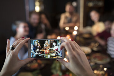 Cropped image of woman photographing friends having meal during Christmas - CAVF44010