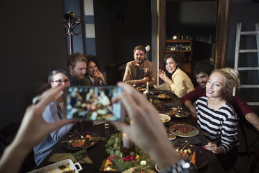 Cropped image of woman photographing happy friends while enjoying meal - CAVF44011