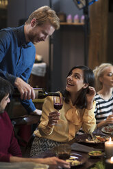 Man pouring wine for female friend during Christmas party - CAVF44012