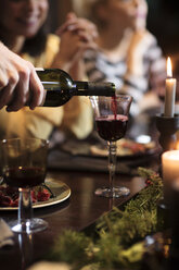 Mann gießt während einer Weihnachtsfeier Wein in ein Glas - CAVF44014