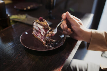 Abgeschnittenes Bild eines Mannes, der am Tisch ein Stück Kuchen isst - CAVF44019