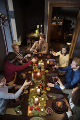 Friends toasting wine while enjoying meal during Christmas - CAVF44024