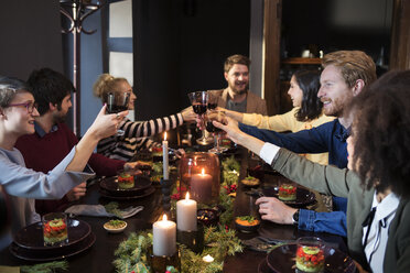 Freunde stoßen mit Wein an und genießen das Essen auf der Weihnachtsfeier - CAVF44025