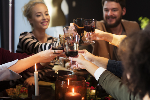 Glückliche Freunde stoßen mit Wein an, während sie eine Weihnachtsfeier genießen, lizenzfreies Stockfoto