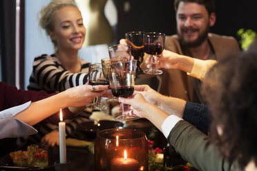 Glückliche Freunde stoßen mit Wein an, während sie eine Weihnachtsfeier genießen - CAVF44029