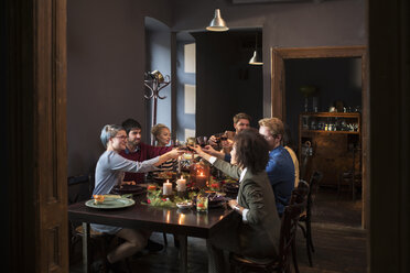 Friends toasting wine while having meal at table during Christmas - CAVF44030