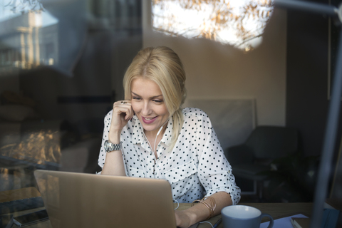 Glückliche Frau mit Laptop im Home Office, lizenzfreies Stockfoto