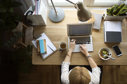 Draufsicht auf eine Frau, die einen Laptop am Tisch im Heimbüro benutzt - CAVF44054