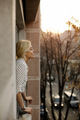 Seitenansicht einer entspannten Frau, die am Hausfenster steht - CAVF44056