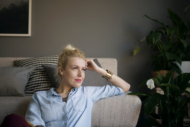 Thoughtful woman leaning on sofa at home - CAVF44061