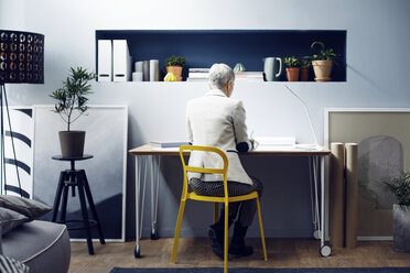 Rückansicht einer Frau, die an einem Tisch in einem kreativen Büro arbeitet - CAVF44071