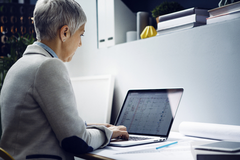 Seriöser Architekt mit Laptop am Tisch im Büro, lizenzfreies Stockfoto