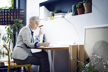 Female architect working while having coffee in office - CAVF44079