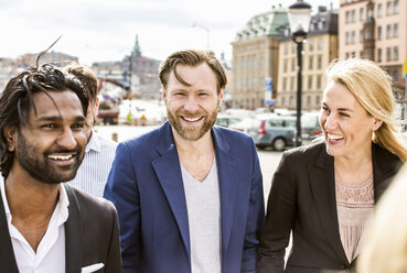 Portrait of mid adult businessman with colleagues standing outdoors - MASF06044