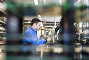 Profilaufnahme eines männlichen Elektrikers bei der Arbeit an einer Platine in der Industrie - MASF06051