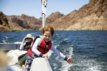 Happy boy traveling in boat with grandmother - CAVF44087