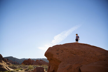 Niedriger Blickwinkel auf einen Jungen, der auf einer Klippe im Valley of Fire State Park vor blauem Himmel steht - CAVF44090