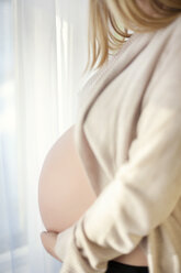 Seitenansicht des Mittelteils einer schwangeren Frau zu Hause - CAVF44093