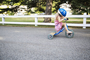 Seitenansicht eines Mädchens auf einem Dreirad auf der Straße mit Helm - CAVF44112