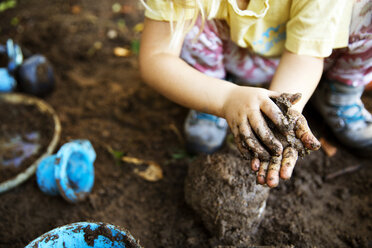 High angle view of girl playing with mud - CAVF44118