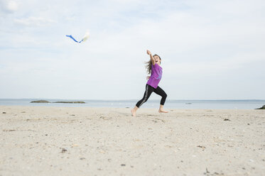 Mädchen spielt mit Drachen am Strand gegen den Himmel - CAVF44150