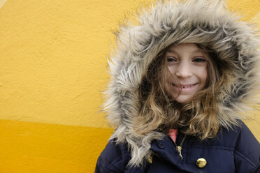 Porträt eines Mädchens in Pelzjacke vor gelber Wand - CAVF44174