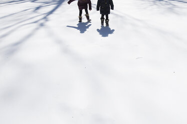 Niedriger Ausschnitt von Schwestern, die auf einem schneebedeckten Feld laufen - CAVF44183