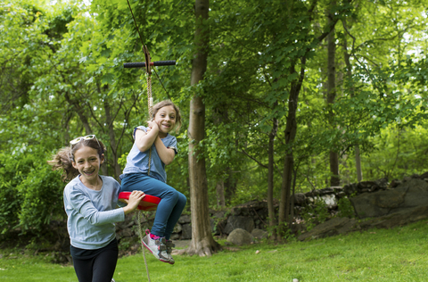 Glückliche Schwestern spielen mit der Seilbahn im Park, lizenzfreies Stockfoto