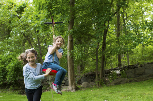 Glückliche Schwestern spielen mit der Seilbahn im Park - CAVF44193