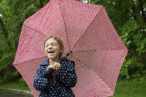 Lachendes Mädchen mit Regenschirm im Park, lizenzfreies Stockfoto