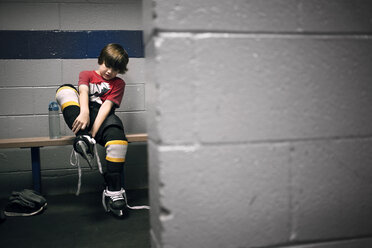 Boy putting on ice hockey skates - CAVF44217