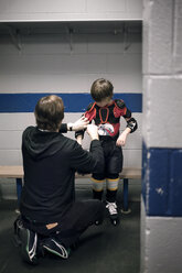 Father helping son with ice hockey uniform - CAVF44219