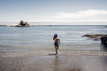 Rear view of woman standing on shore against sky - CAVF44252