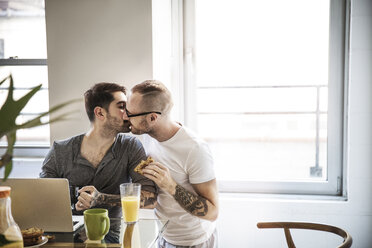 Homosexuelles Paar, das sich beim Frühstück am Tisch vor dem Fenster küsst - CAVF44280