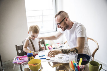 Lächelnder Vater zeichnet mit seiner Tochter beim Frühstück am Tisch - CAVF44286