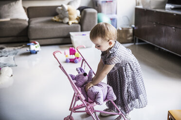 Mädchen spielt mit Plüschtier im Wohnzimmer zu Hause - CAVF44296