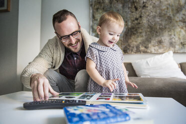 Glücklicher Vater liest seiner Tochter zu Hause ein Bilderbuch vor - CAVF44301