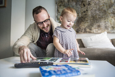 Happy father reading picture book to daughter at home - CAVF44301