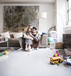 Loving fathers embracing girl while sitting in living room at home - CAVF44306