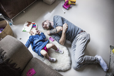 Blick von oben auf einen glücklichen Vater und eine Tochter, die zu Hause auf dem Boden liegen - CAVF44312
