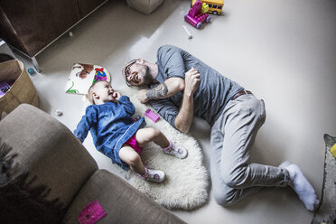 High angle view of happy father and daughter lying on floor at home - CAVF44312