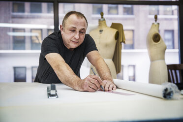 Fashion designer working at table in design studio - CAVF44331