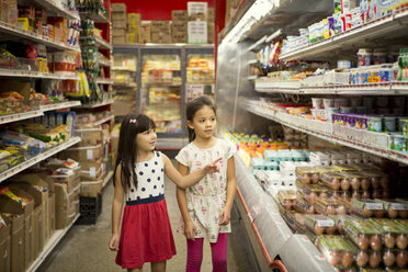 Mädchen schauen sich verschiedene Produkte in den Regalen eines Supermarkts an - CAVF44384