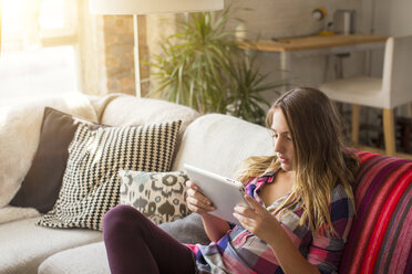 Hohe Winkel Ansicht des Mädchens mit Tablet-Computer beim Sitzen auf dem Sofa zu Hause - CAVF44388