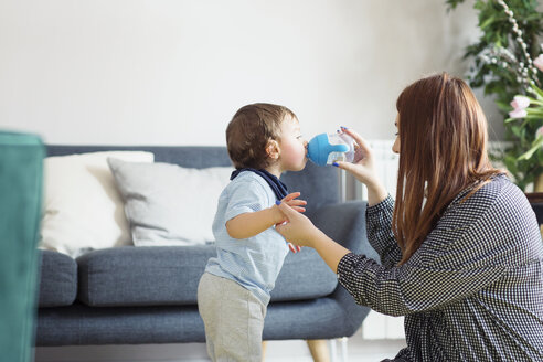 Mutter hilft ihrem Sohn beim Wassertrinken zu Hause - CAVF44464