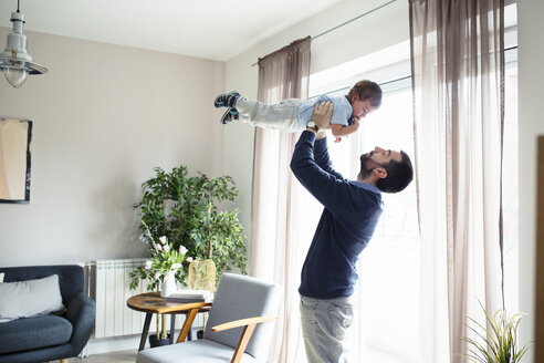 Verspielter Mann mit Sohn am Fenster stehend zu Hause - CAVF44470